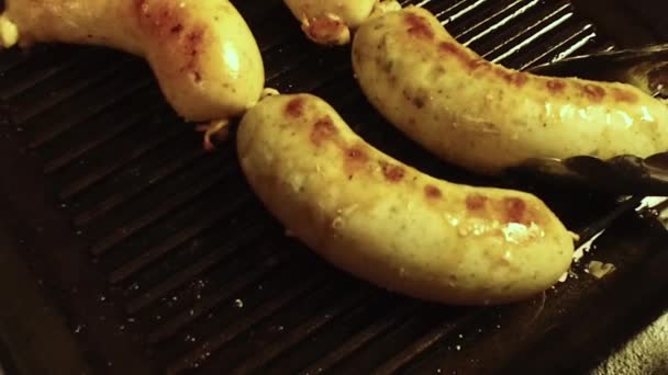 钳子旋转烤香肠在一个黑色的烧烤勺 — 图库视频影像