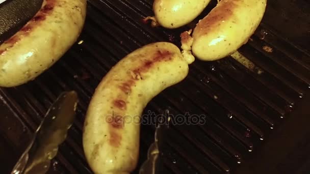 在烤架上准备香肠 钳子把油炸的德国德国在一个黑色的瓦罐上 — 图库视频影像