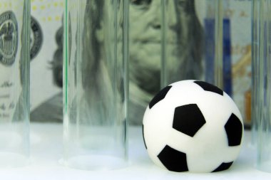 Yüz dolarlık banknot çerçevede tıbbi test tüpleri ile Hediyelik eşya futbol topu. Kavram para ve spor, tıp ve futbol, yolsuzluk ve doping. Makro. Süper yakın çekim.