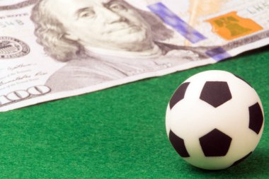 Makro. Bir futbol topu yeşil bir arka plan ve 100 dolar. Kavram para ve spor, futbol, bir oyuncunun maaş bahis. Süper yakın çekim.