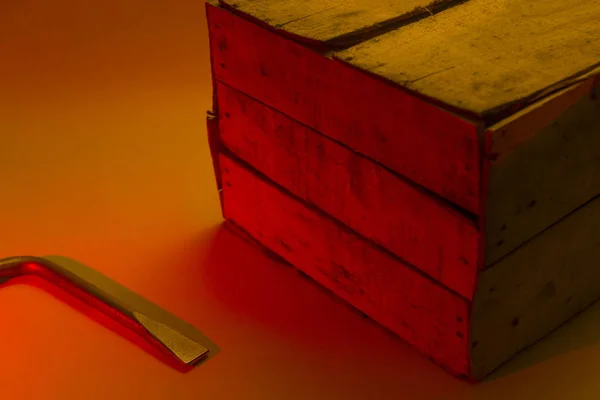 Rode niveau van gevaar. Het hulpprogramma voor het koppelen ligt in de buurt van de houten kist in helder rood-oranje licht. Kopieer ruimte. Opgelet, breken — Stockfoto