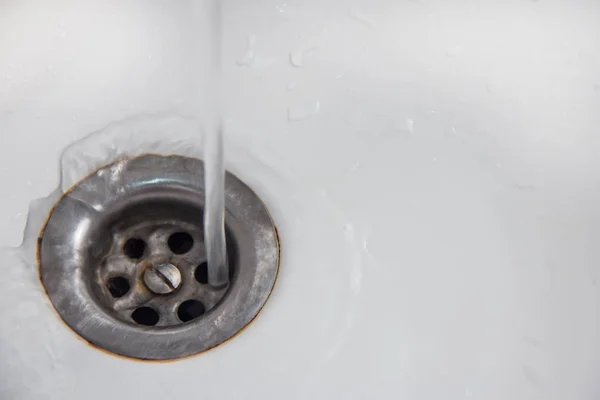 Save water A jet of water gets directly into the drain hole in a white sink or bathtub.