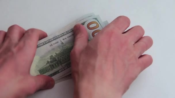 男性的手举起一叠美国百元钞票从白色桌并且折叠他们在一半。1000美元。关闭。白色背景。贿赂或薪水。贪污或商业. — 图库视频影像