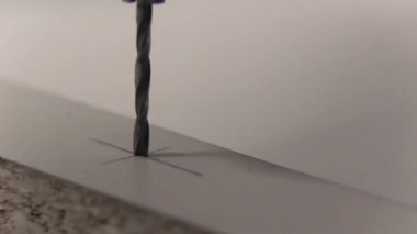Makro. Yakın çekim. Beyaz mobilya için bir Sunta içinde bir matkap ile delik delme.