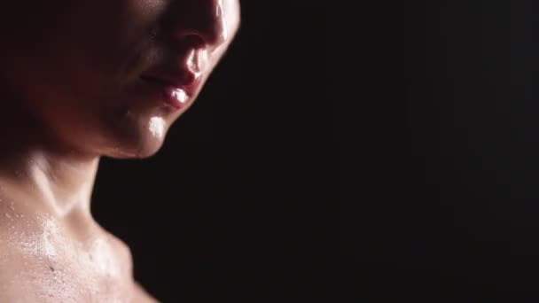 The lower part of the face of an Asian man on a dark background. Drops of water or sweat on the nose, lips and chin. Close-up. — Stock Video