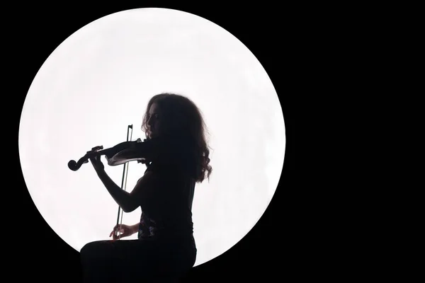 Sziluettje egy lány egy fehér kör a hegedű, a kezében. Koncepció. Zene a telihold. Éjszakai háttér. Másolja a hely. — Stock Fotó