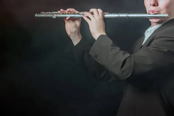 Bir close-up elinde ve bir müzisyen dudaklarında bir flüt. Adam duman ile karanlık bir arka plan sesleri alır. Kopya alanı.