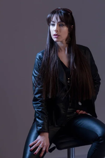 Portrait of a sexy beautiful girl with long hair in black leather clothes. Studio fashion photography. Gray background. — Stock Photo, Image