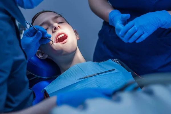Tandheelkundige behandeling met tandheelkundige genezen van licht. Tiener in de tandheelkunde. — Stockfoto