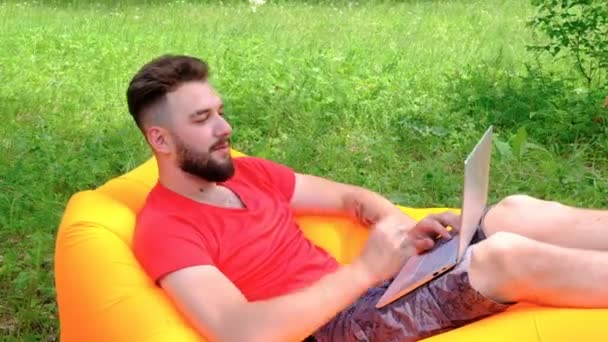 Facet Czerwonej Koszulce Pracuje Laptopie Mężczyzna Brodą Leży Nadmuchiwanej Sofie — Wideo stockowe