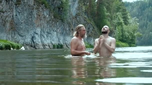 一个年轻人和一个老人在山河里洗澡 像祈祷者一样向天空沐浴和凝视 水落石出的游戏 开玩笑的 — 图库视频影像