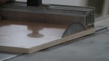 İşçi, yonga tahtasının kenarını dairesel testereyle testereyle kesiyor. Yakın plan. Mobilya imalatı. Video gerçek ses ve gürültü içeriyor..