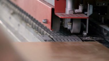 Mobilya imalatı. Çip parçalarını kesen makine. İşçi elleri kenarı yapıştırmak için kullanılacak parçaya rehberlik eder. Yakın plan. Seçici odaklanma. Video gerçek ses ve gürültü içeriyor..