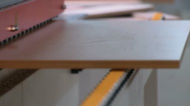 Mobilya imalatı. Kenarları yapıştırmak için yonga tahtasının bir kısmı makineden geçiyor. Video gerçek endüstriyel ses ve gürültü içeriyor. Seçici odaklanma. Yakın plan..