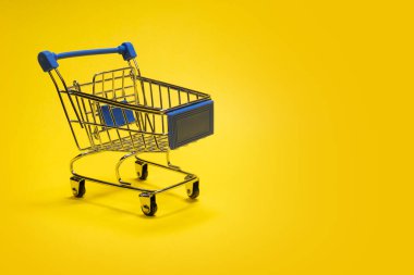 Alışveriş için hediye bebek arabası. Sarı arka plan. Uzayı kopyala Çevrimiçi veya çevrimdışı reklam alımları için şablon. İndirim ve satış kavramı, bir alıcının veya satıcının iş ve alışveriş arabası.
