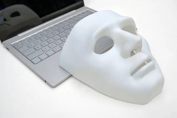 Maska, laptop na bílém pozadí. Koncept kybernetického útoku nebo obrany proti hackerům. Detailní záběr. — Stock fotografie