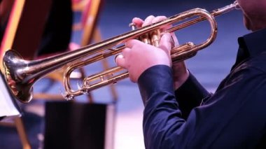 Adam trompeti çalmayı bitirir ve çarşafı notalarla çevirir. Konser. Bir bando müzisyeni..