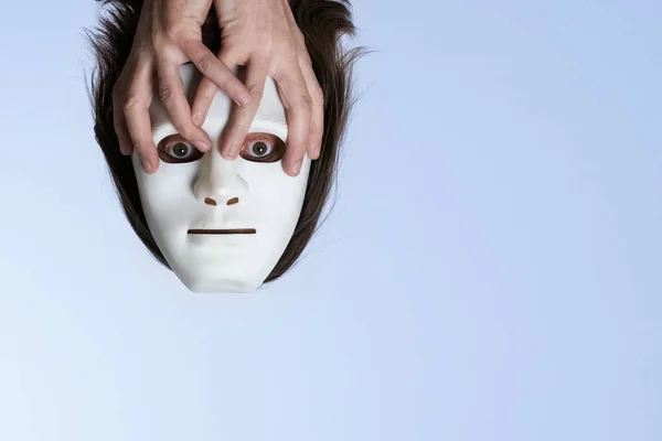 Head of a man in a white mask under the ceiling. Men's hands hold a flying face. Surrealistic picture of the soul. The concept of concealment of personality, mental problems, split personality. — Stock Photo, Image