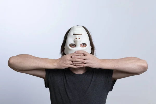 Um homem cobriu seu rosto com uma máscara invertida e segura seus cotovelos para os lados com os dedos apertados juntos.Conceito surrealista da busca pelo sentido da vida ou uma visão diferente do mundo. — Fotografia de Stock