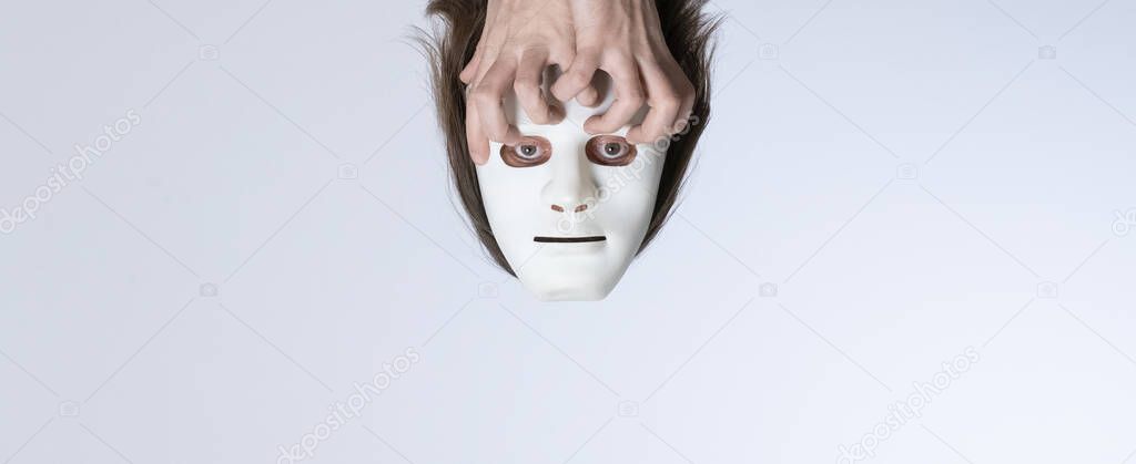 Psychedelic surrealistic concept. Lost thoughts. The head in a white mask without a body is held by crooked fingers. Template for banner design for psychology, esoterics, psychotherapy and occultism.