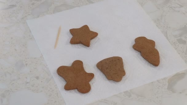 Dětská ruka položí cookies na stůl, aby obarvila sváteční loy. Vánoční perníkové sušenky na ubrousku. Pohyb fotoaparátu při fotografování handheldu. — Stock video