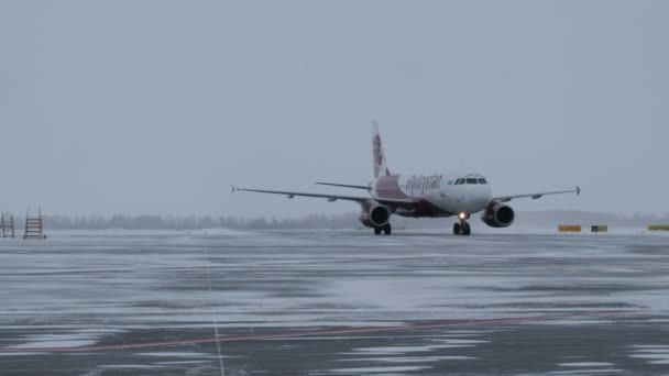 2019-12-18 Kostanay, Kazakhstan. Penerbangan pertama dari perusahaan udara FlyArystan dari Nur-Sultan ke Qostanay. Pendaratan pesawat Airbus A320 di lapangan terbang musim dingin. Pengawal pesawat dengan mobil Niva . — Stok Video