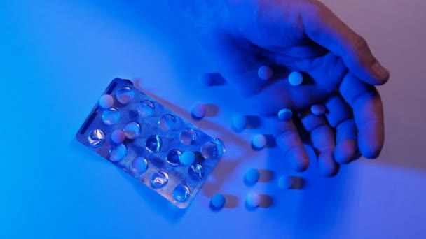 男性の手と混沌とした散乱錠剤 ライトが救急車のサイレンのように青く点滅する 危険性と麻薬物質の概念 過剰摂取と自殺 犯罪や薬物 社会問題 — ストック動画