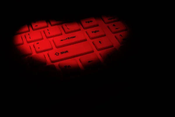 Ένα πληκτρολόγιο υπολογιστή τονίζεται με κόκκινο χρώμα σε σχήμα καρδιάς. Η έννοια του likes και της αγάπης στον ψηφιακό κόσμο του Διαδικτύου. Μαύρο φόντο. Αντιγραφή χώρου. — Φωτογραφία Αρχείου