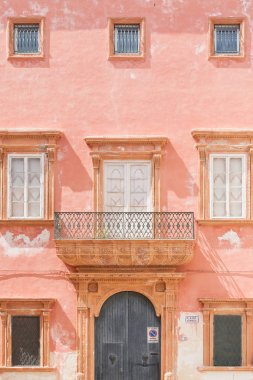Gallipoli, Apulia - A pink facade with a barn door and several w clipart