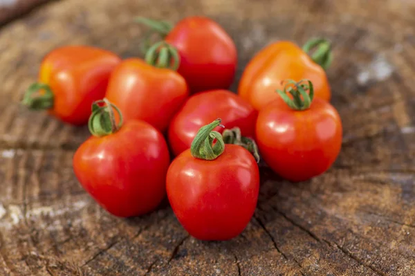 Grupo de tomates de morango crus vermelhos saborosos amadurecidos em madeira no contexto natural verde, verduras sãs saborosas ainda vida — Fotografia de Stock
