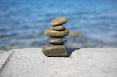 Beş taş cairn kulesi, kaya zen heykeli, kahverengi bej çakıl taşları ve açık mavi arkaplan