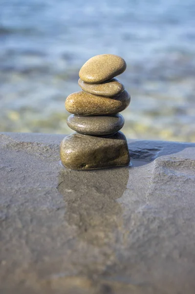 Beş taş cairn kulesi, kaya zen heykeli, kahverengi bej çakıl taşları ve açık mavi arkaplan