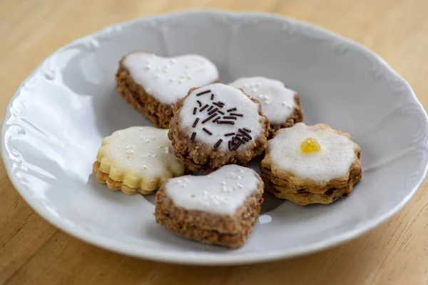 Gem și smântână umplut cookie-uri cu zahăr dulce glazură albă pe placă albă pe masă de lemn, grup de dulciuri de Crăciun — Fotografie, imagine de stoc