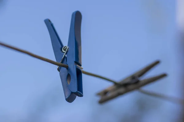 Skupina plastových a dřevěných kolíků na prádlo zavěšených na šňůře proti modré obloze — Stock fotografie