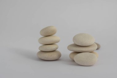 Beyaz zemin üzerinde izole edilmiş iki basitlik taşı, kule, ahenk ve denge içinde dört ve beş beyaz çakıl grubu