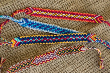 El yapımı, renkli, doğal, dokuma bilezikler jüt arka planda izole edilmiş arkadaşlık bilezikleri.