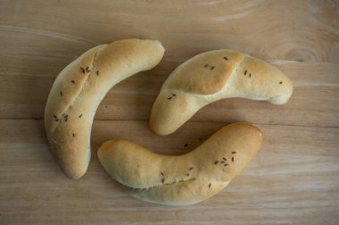 Üç ev yapımı kruvasan rulo kimyon serpiştirilmiş, ahşap masada çok taze ve çıtır çıtır fırınlar, altın fırınlanmış.