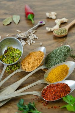 Ahşap masa üzerinde kaşık içinde çeşitli baharatlar