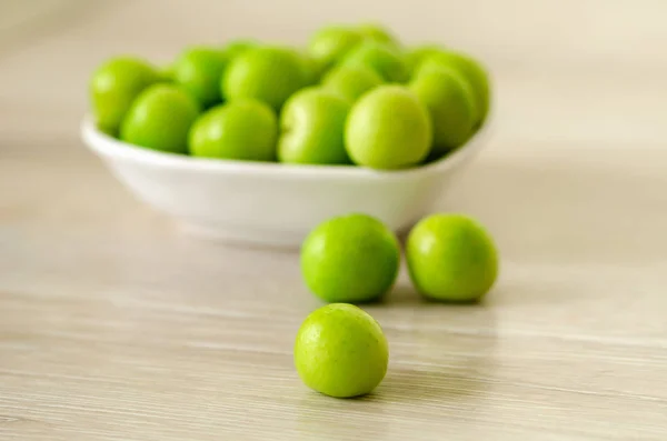 Miskę świeży zielony śliwki na stole — Zdjęcie stockowe