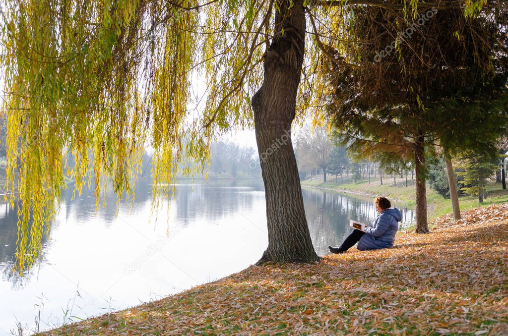 The woman is reading a magazine  by the river 