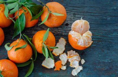 Tahta masada taze mandalina ve yaprak var.