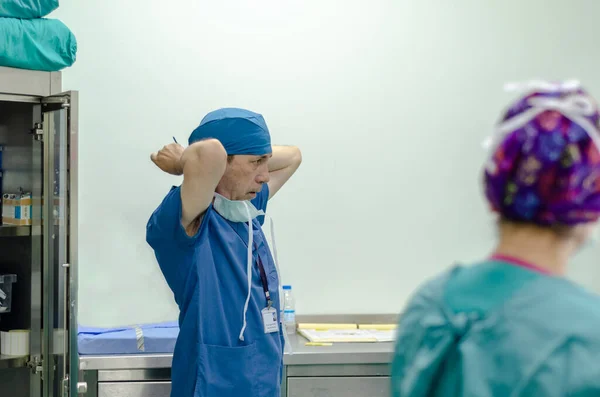 外科医は準備で外科用キャップを結びます サイドビュー ロイヤリティフリーのストック写真
