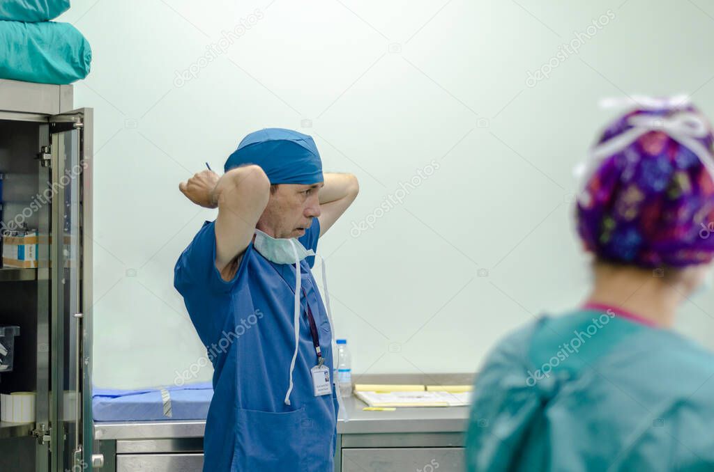 Surgeon tying surgical cap in preparation, side view
