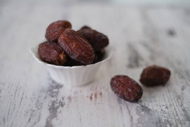 Beyaz bir kasede olgunlaşmış hurmalar. İslam ülkesinde önemli bir meyve. Kutsal Ramazan ayında kahvaltı için sağlıklı ve besleyici bir besin..