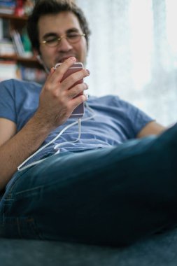 Arkadaşlarıyla yaptığı video görüşmesi sırasında akıllı bir telefonu tutan bir erkeğin yakın çekimi.