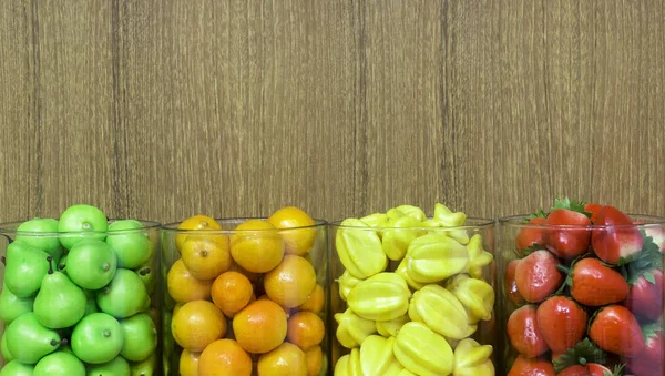 Frutas falsas em uma mesa de madeira, frutas plásticas em frasco de vidro com — Fotografia de Stock
