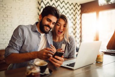 Genç çift kafede alışveriş online. Adam banka hesabını kontrol.