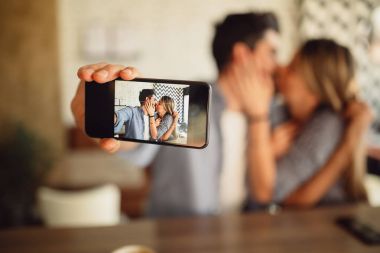 İnternet kafede öpüşme sırasında arka kamera ile çift alarak selfie. Cep üzerine sığ odak.