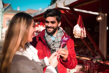 Romantik Çift ayakta gülümseyen ve bazı tatlı lolipop satın sokakta. Yıldönümü, Sevgililer günü.