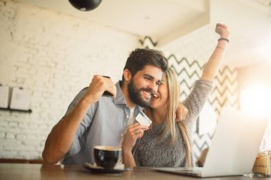 Laptop ve kafede kredi kartı ile online alışveriş yaparken mutlu çift.